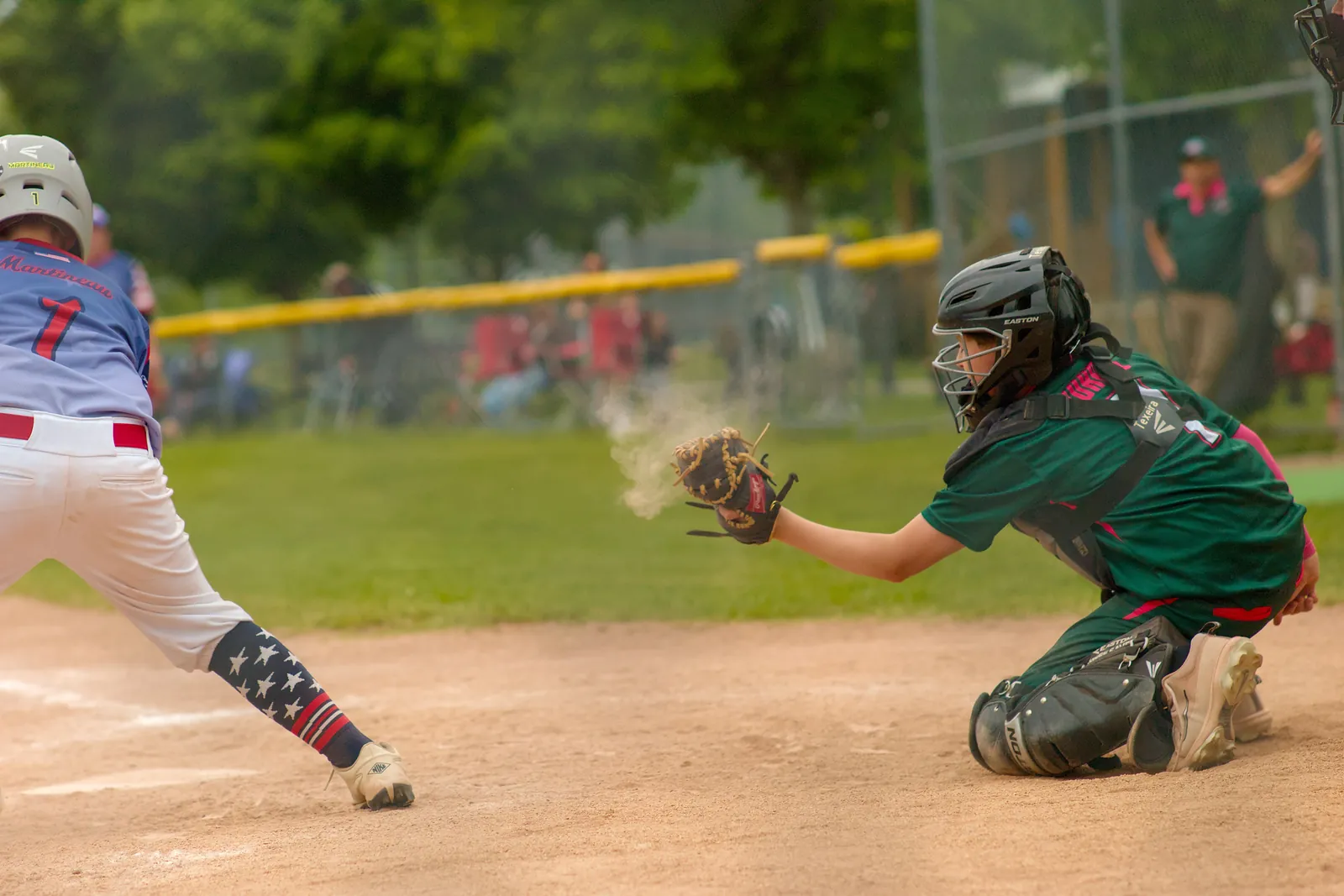 The Rizzlers catcher catches a pitch in a puff of dust