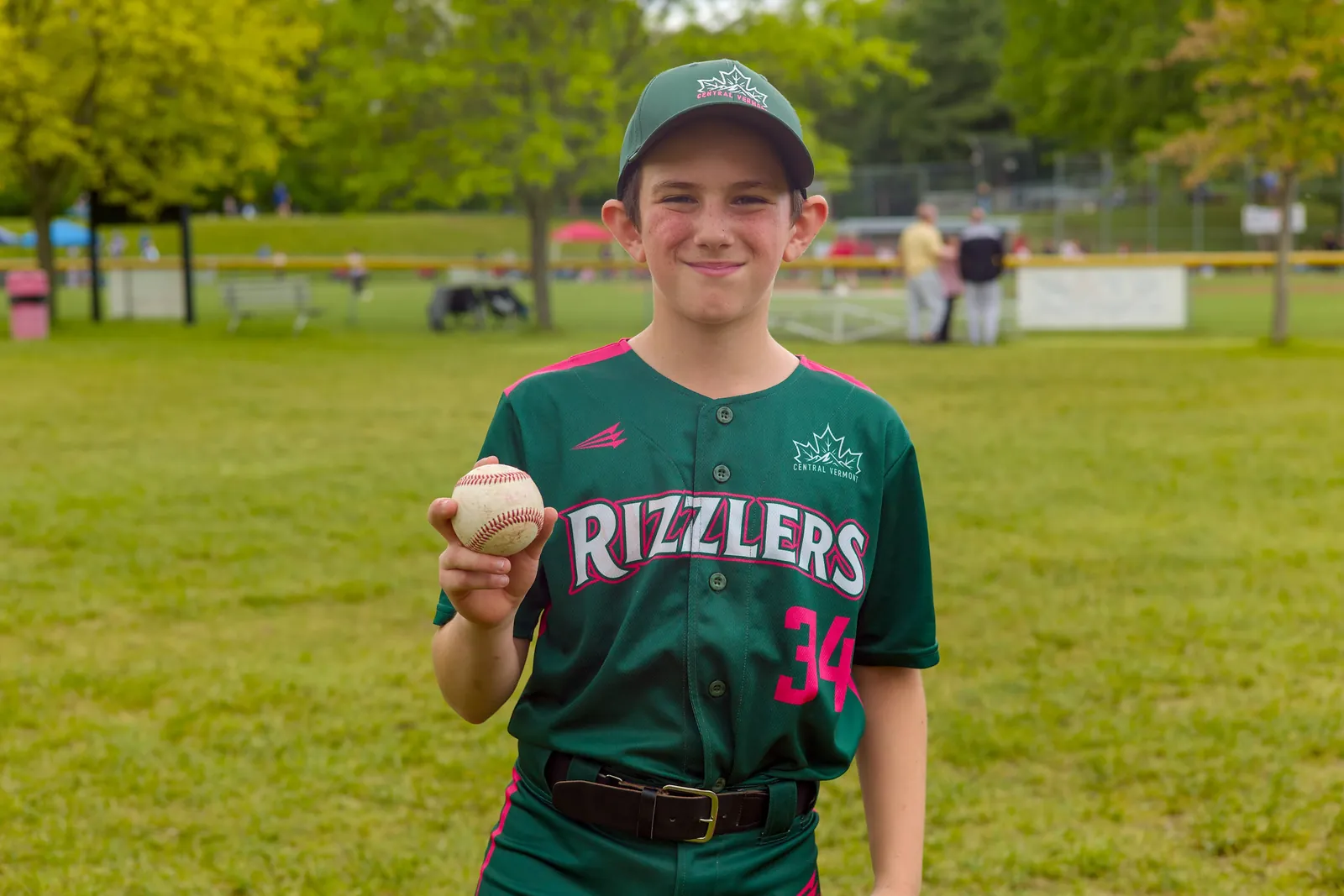 A smiling Rizzlers player holding up a baseball