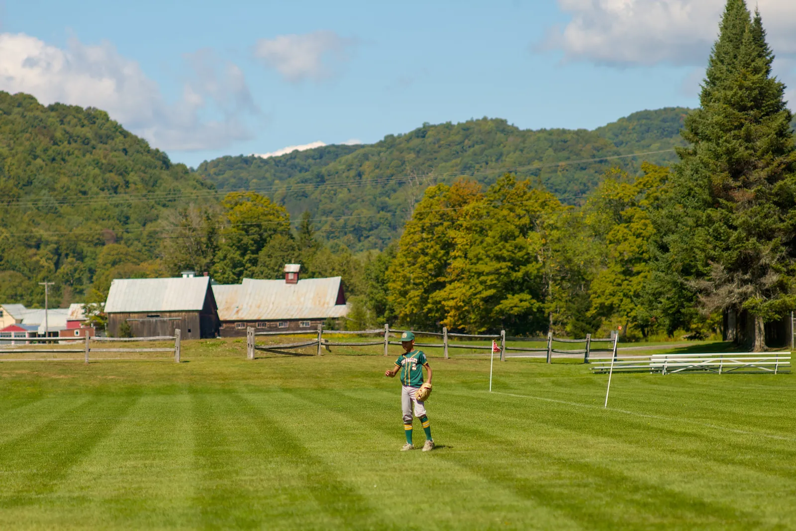 A Rizzlers outfielder on a field with Vermont hills behind