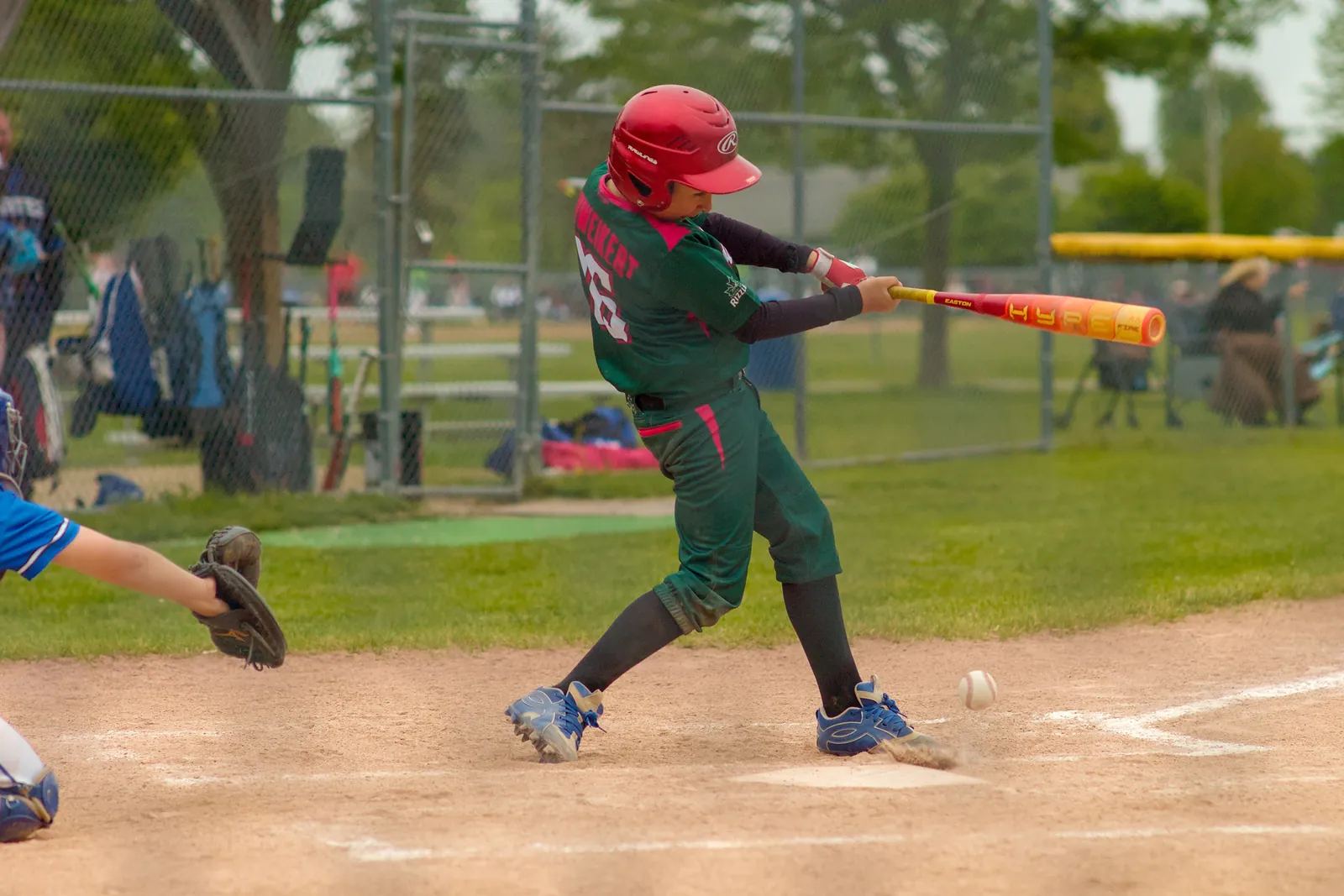 A Rizzlers batter in a red helmet makes contact