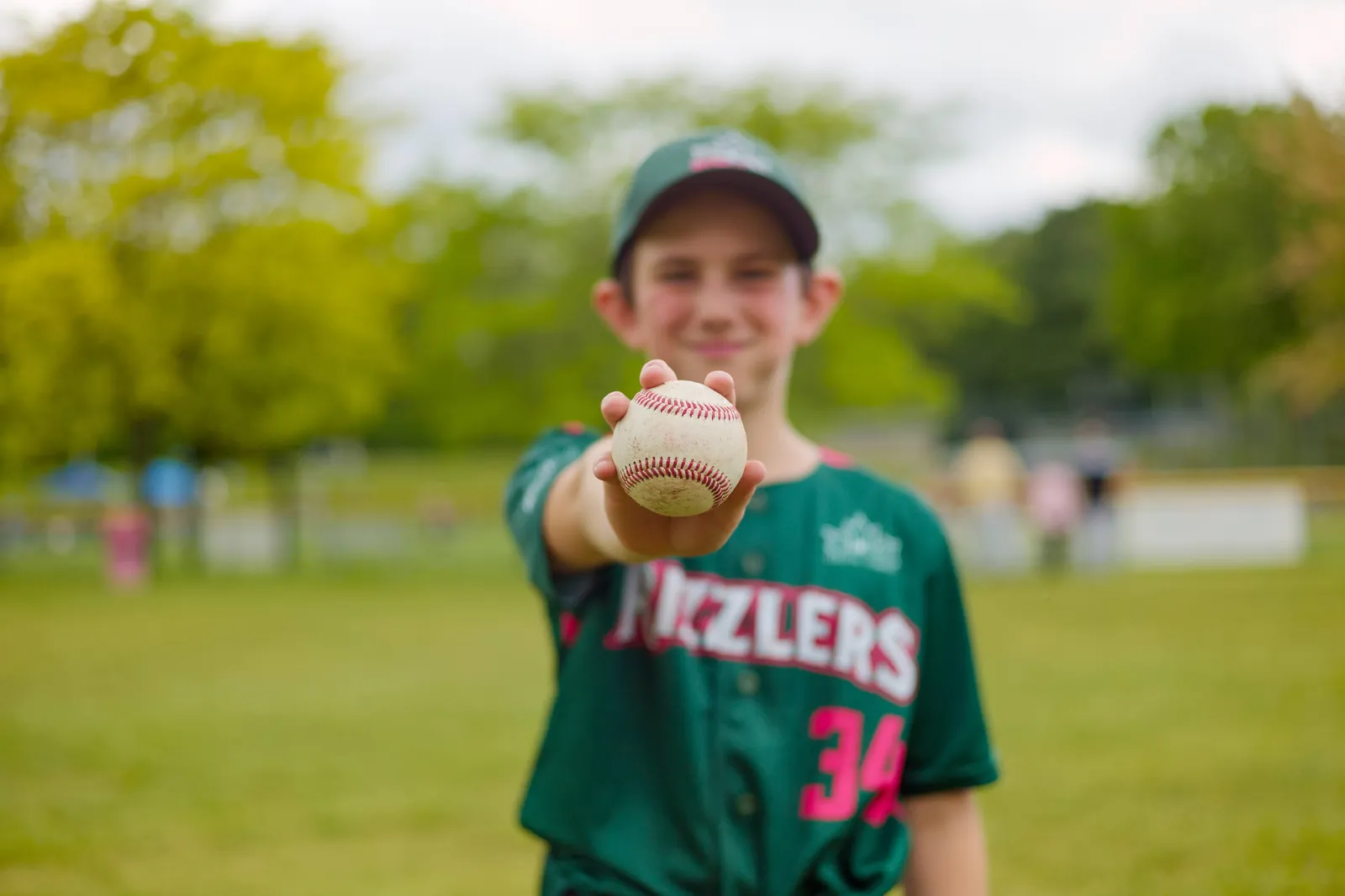 A Rizzlers player holds a baseball out toward the camera