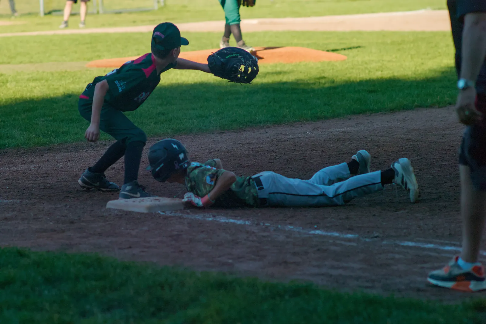 A Rizzlers player tags a runner diving back to base