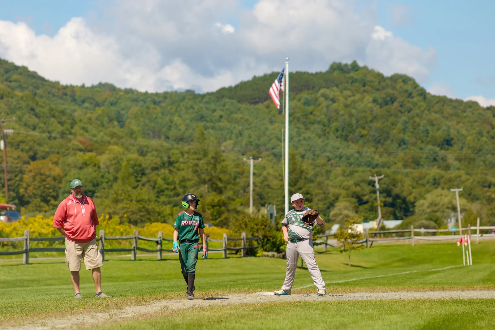 A Rizzlers player on a field below a wooded hill